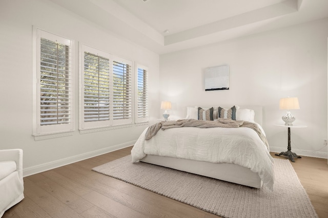 bedroom with hardwood / wood-style flooring and a tray ceiling