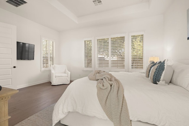 bedroom with dark hardwood / wood-style flooring and a tray ceiling