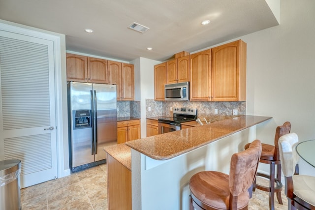 kitchen with tasteful backsplash, a breakfast bar area, stainless steel appliances, and kitchen peninsula