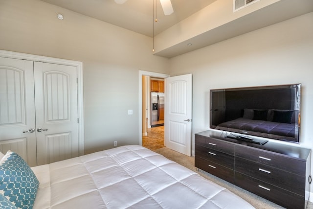 bedroom featuring ceiling fan, light colored carpet, stainless steel fridge, and a closet