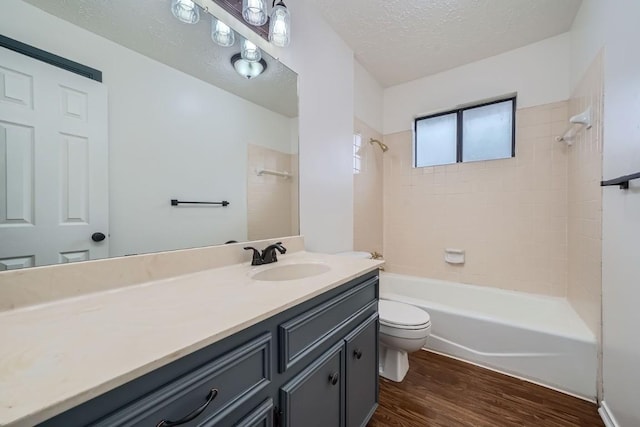 full bathroom featuring toilet, tiled shower / bath, a textured ceiling, vanity, and hardwood / wood-style floors