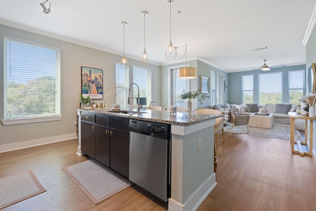 kitchen featuring hanging light fixtures, an island with sink, sink, and stainless steel dishwasher