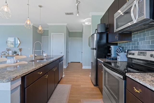 kitchen featuring pendant lighting, sink, backsplash, and appliances with stainless steel finishes