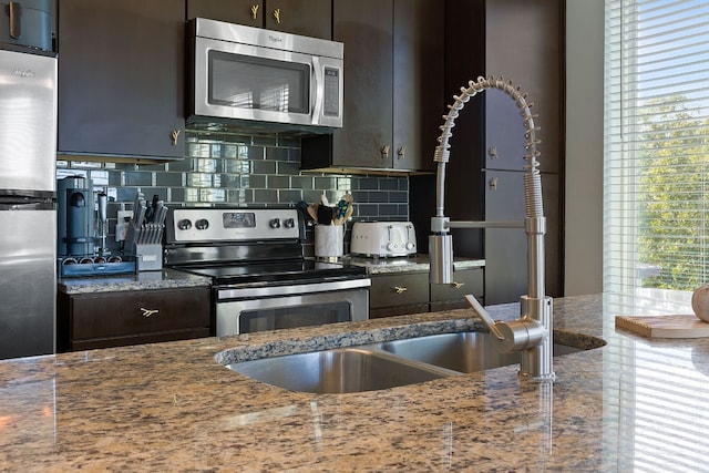 kitchen featuring appliances with stainless steel finishes, dark brown cabinets, a wealth of natural light, and decorative backsplash