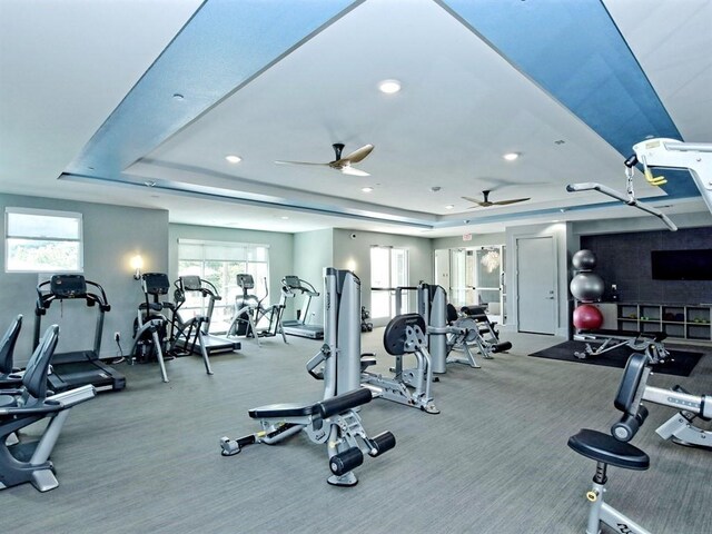 exercise room featuring carpet floors, a raised ceiling, and ceiling fan