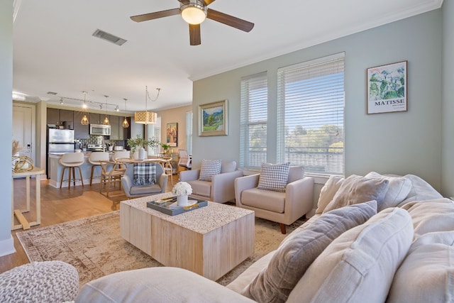 living room with crown molding, ceiling fan, and light hardwood / wood-style flooring