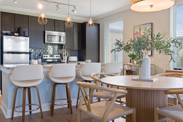 kitchen featuring appliances with stainless steel finishes, dark hardwood / wood-style floors, backsplash, and a kitchen bar