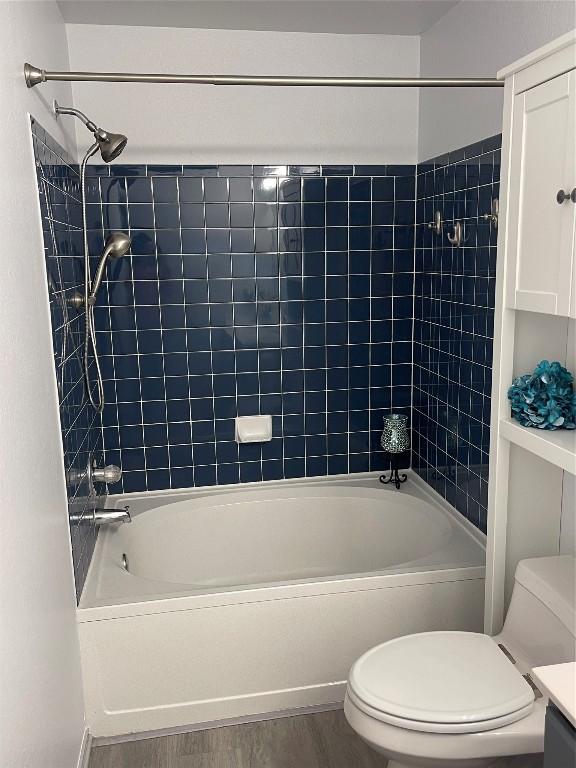 full bathroom featuring hardwood / wood-style flooring, tiled shower / bath, vanity, and toilet