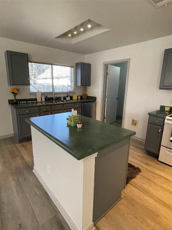 kitchen featuring gray cabinets, a kitchen island, stove, and light hardwood / wood-style floors