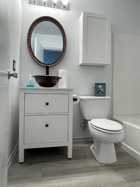 full bathroom with vanity, tub / shower combination, hardwood / wood-style floors, and toilet