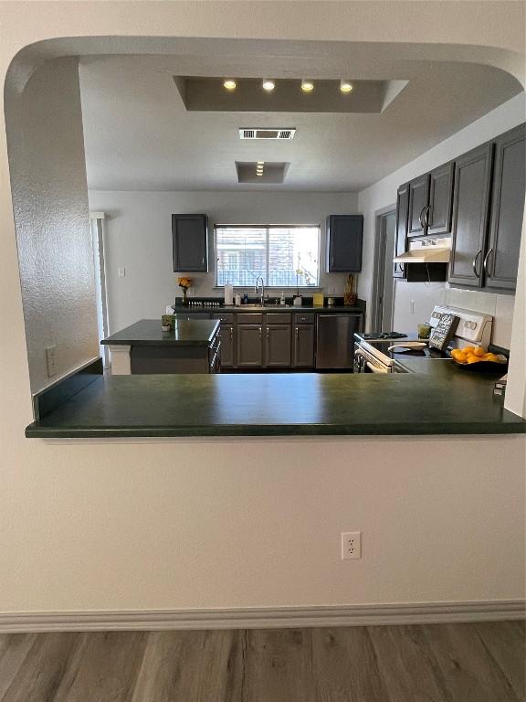 kitchen with stove, dark hardwood / wood-style flooring, and kitchen peninsula