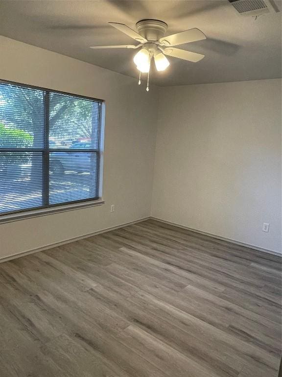 empty room with hardwood / wood-style floors, a wealth of natural light, and ceiling fan