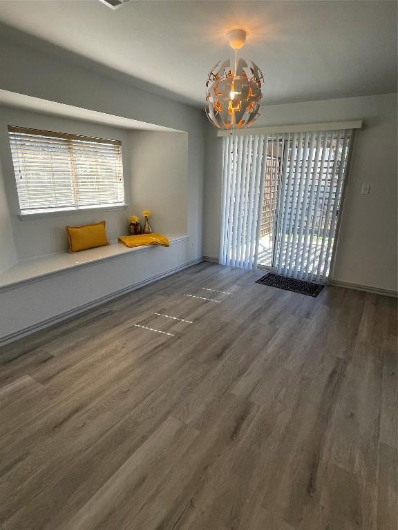 unfurnished dining area with a notable chandelier and dark wood-type flooring