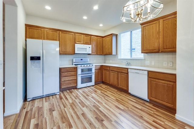 kitchen with pendant lighting, sink, white appliances, backsplash, and light hardwood / wood-style floors