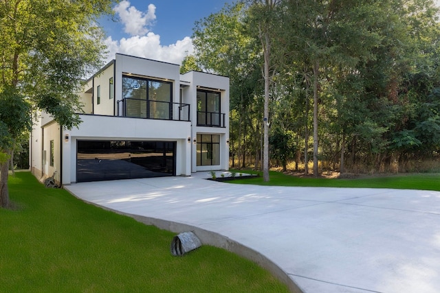 modern home featuring a garage, a balcony, and a front yard