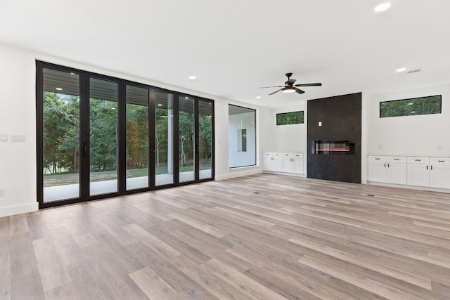 unfurnished living room featuring floor to ceiling windows, ceiling fan, and light hardwood / wood-style flooring