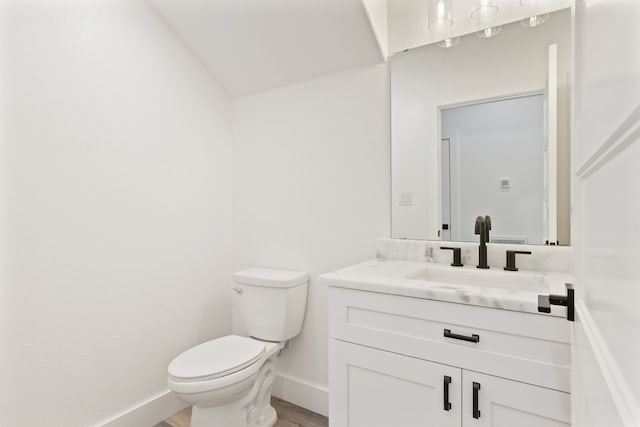 bathroom featuring vanity, hardwood / wood-style flooring, vaulted ceiling, and toilet