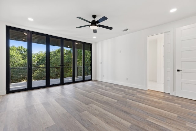 unfurnished room featuring floor to ceiling windows, ceiling fan, and light wood-type flooring