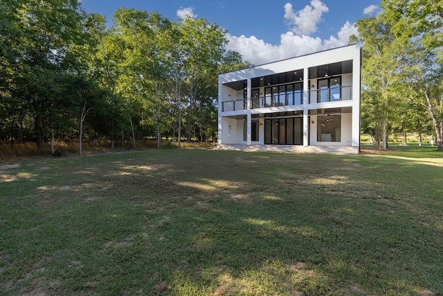 rear view of house with a balcony and a yard