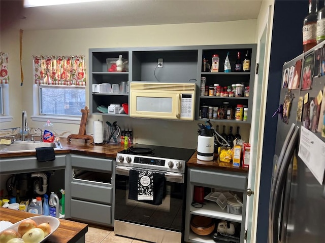 kitchen featuring butcher block countertops, light tile patterned floors, stainless steel appliances, and sink