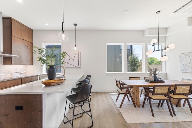 kitchen featuring a kitchen bar, sink, light hardwood / wood-style flooring, kitchen peninsula, and pendant lighting