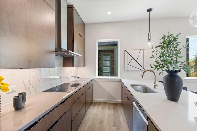 kitchen with black electric stovetop, a sink, wall chimney range hood, dishwasher, and pendant lighting