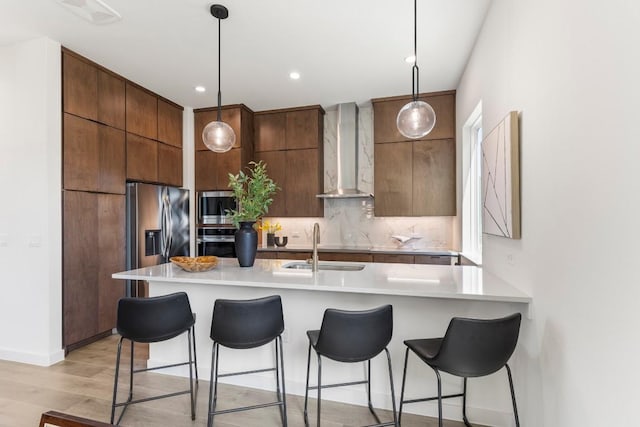 kitchen with light countertops, wall chimney range hood, modern cabinets, and pendant lighting