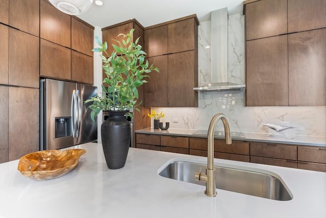 kitchen with wall chimney exhaust hood, modern cabinets, tasteful backsplash, and stainless steel fridge with ice dispenser