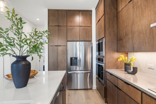 kitchen with light wood-style floors, modern cabinets, stainless steel appliances, and light countertops