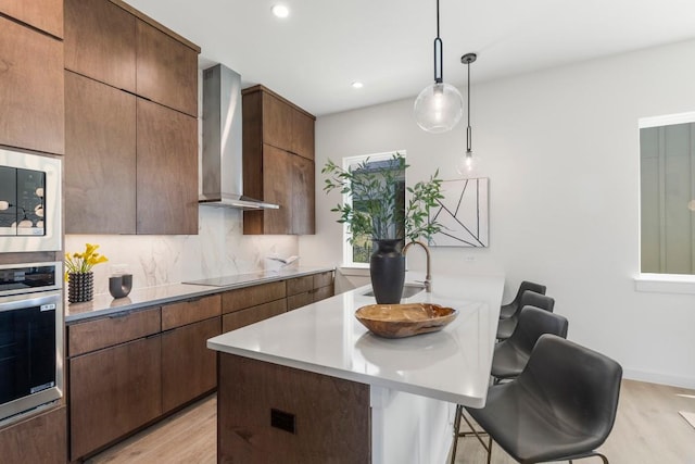 kitchen with modern cabinets, a kitchen breakfast bar, oven, black electric stovetop, and wall chimney range hood