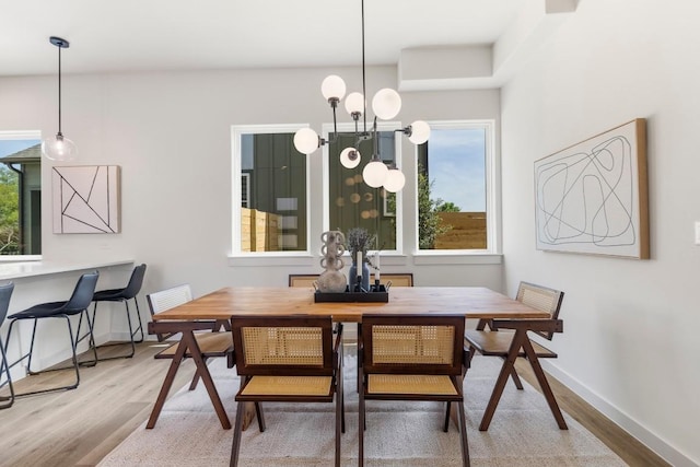 dining space featuring an inviting chandelier, wood finished floors, and baseboards