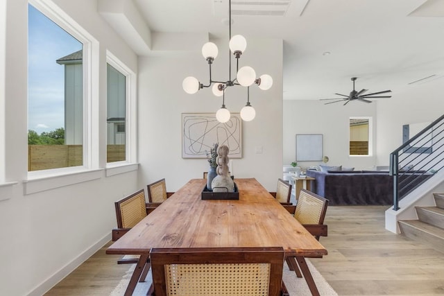 dining space featuring baseboards, stairway, ceiling fan with notable chandelier, and light wood-style floors