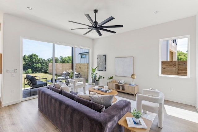 living area featuring light wood-style floors, ceiling fan, and baseboards