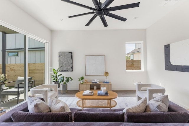 living room featuring a ceiling fan, baseboards, and wood finished floors