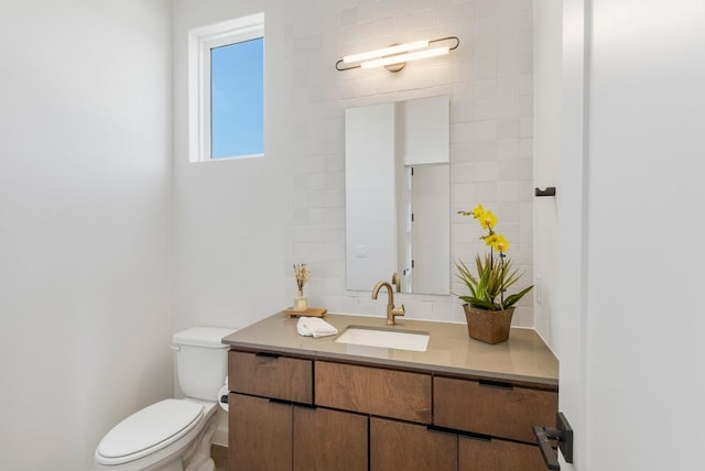 half bath with toilet, tile walls, and vanity