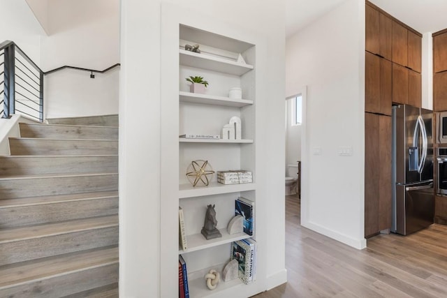 stairway featuring baseboards, built in features, and wood finished floors