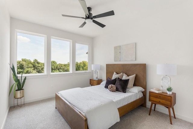 bedroom with light carpet, baseboards, and a ceiling fan