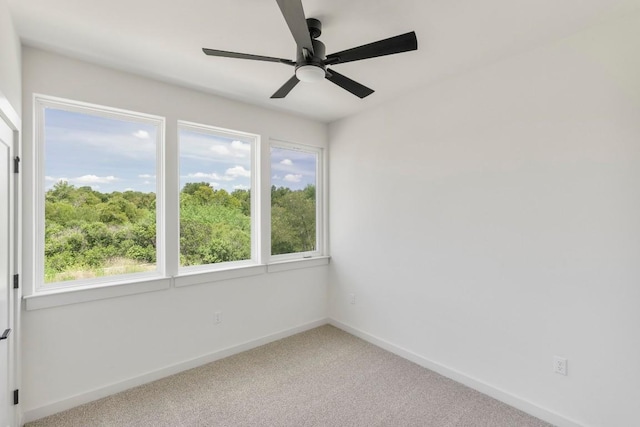 carpeted spare room with baseboards and a ceiling fan