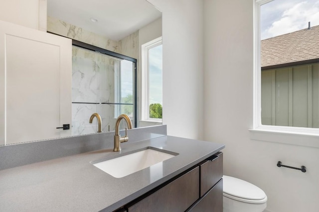 bathroom with a stall shower, vanity, and toilet