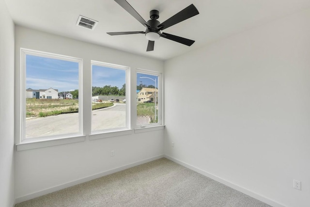 carpeted spare room featuring visible vents, ceiling fan, and baseboards