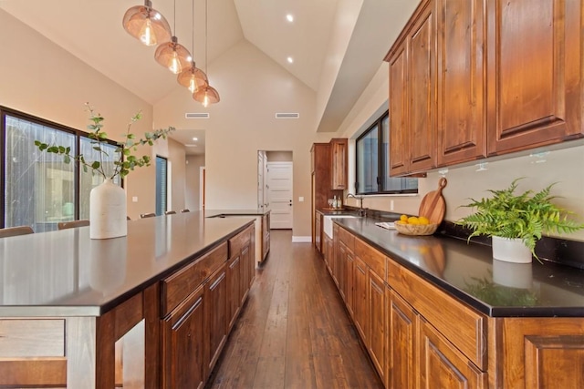 kitchen featuring sink, high vaulted ceiling, dark hardwood / wood-style floors, a center island, and decorative light fixtures