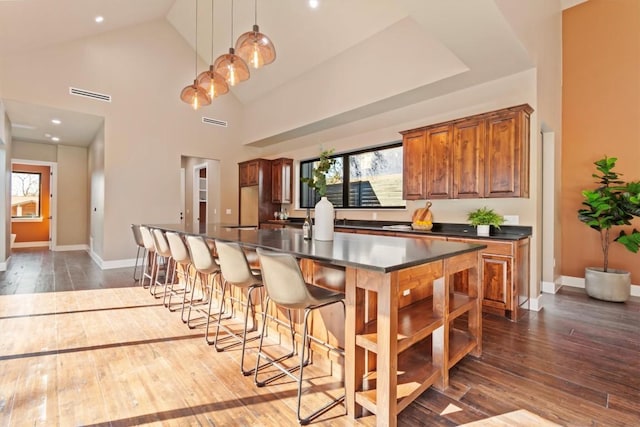 kitchen with hanging light fixtures, dark wood-type flooring, high vaulted ceiling, and a center island