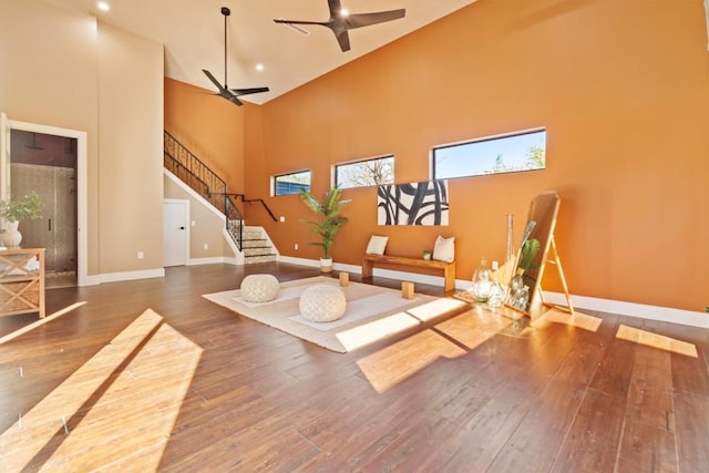 interior space featuring dark wood-type flooring, ceiling fan, and a towering ceiling