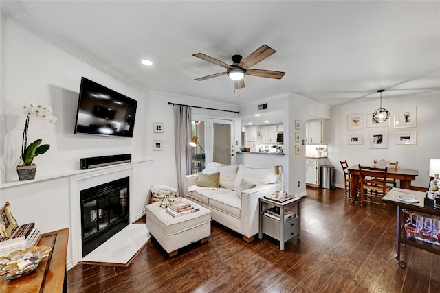 living room with crown molding, dark hardwood / wood-style floors, and ceiling fan