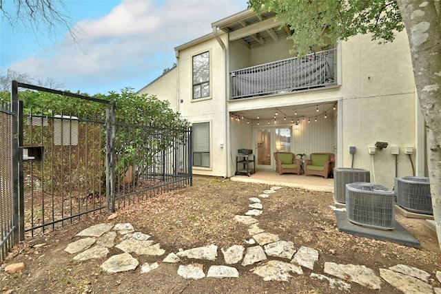 back of property with cooling unit, an outdoor living space, a patio area, and a balcony