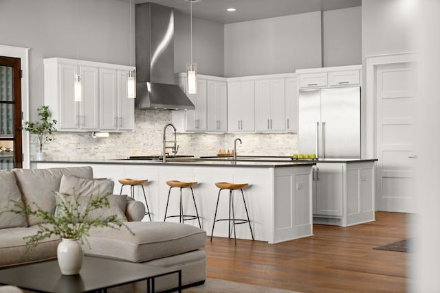 821 Laughing Dog Ct, Leander, TX 78641 - kitchen with wall chimney exhaust hood, built in refrigerator, a high ceiling, dark countertops, and a breakfast bar area