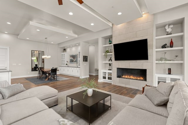 living room featuring hardwood / wood-style floors, a notable chandelier, a fireplace, and built in features