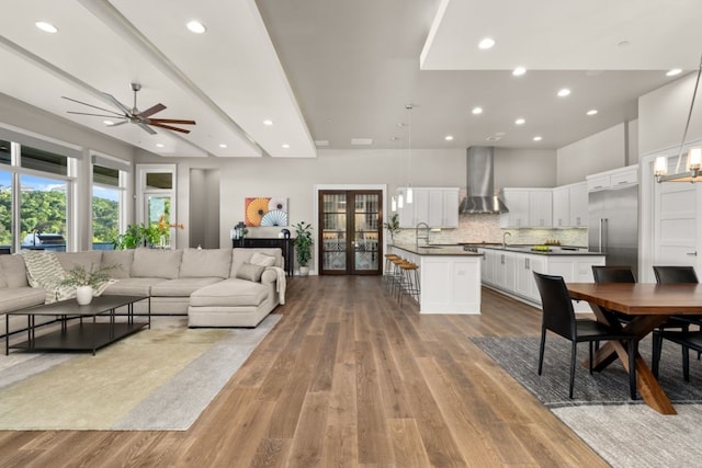 living room featuring french doors, beam ceiling, sink, and light hardwood / wood-style flooring