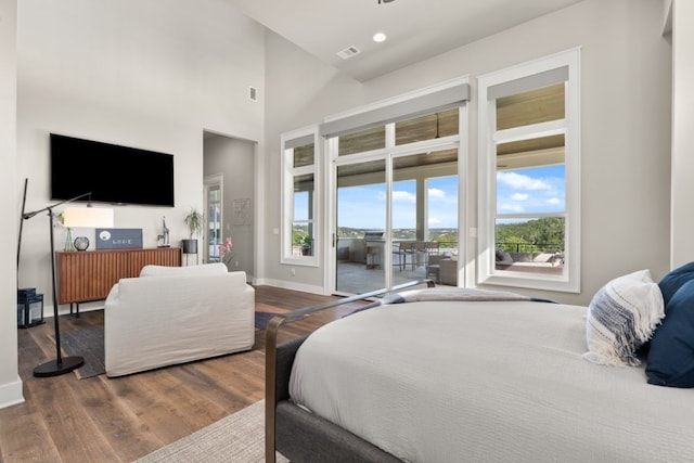 bedroom with a high ceiling, hardwood / wood-style floors, and access to exterior