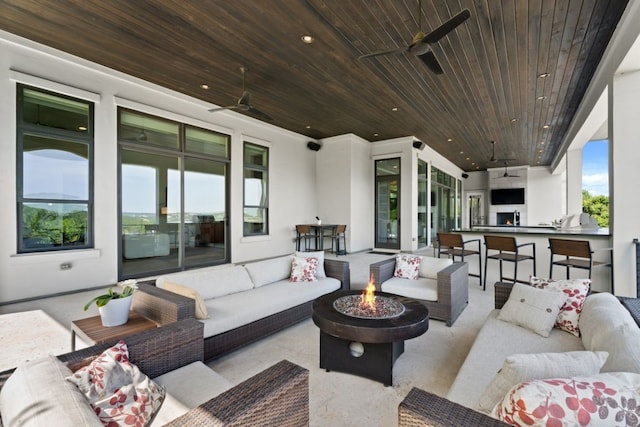 view of patio with an outdoor living space with a fire pit, ceiling fan, and exterior bar